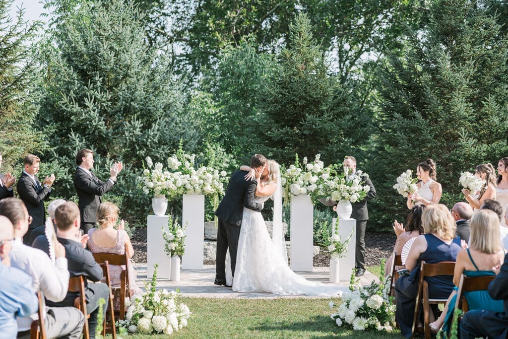 Bride and groom exchanging vows during an outdoor wedding ceremony surrounded by family and friends at Venue3Two.